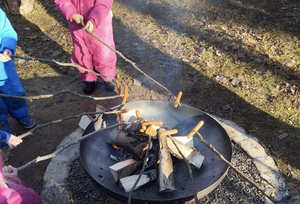 Am Lagerfeuer werden Würstchen gegrillt.