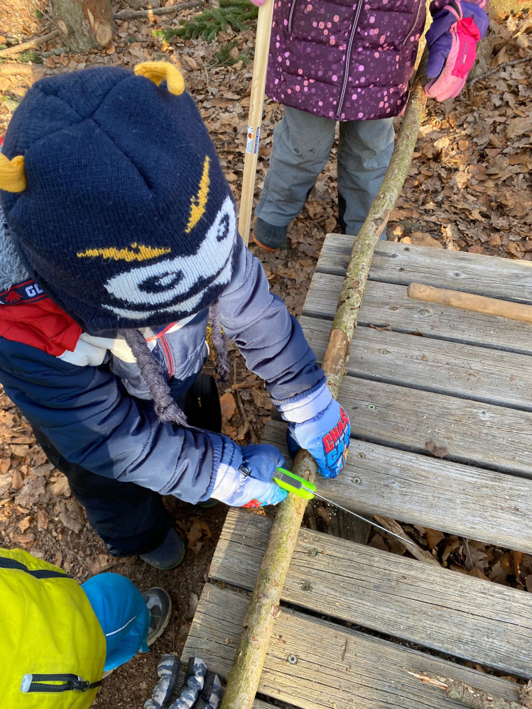 Die Kinder lernen wie man richtig mit einer Säge umgeht.